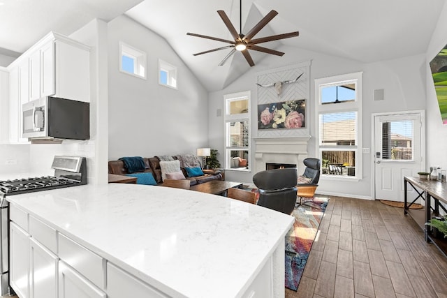 kitchen featuring hardwood / wood-style floors, ceiling fan, white cabinets, and gas range oven