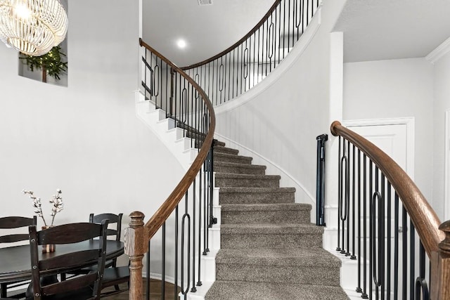 stairs featuring crown molding, hardwood / wood-style floors, and an inviting chandelier