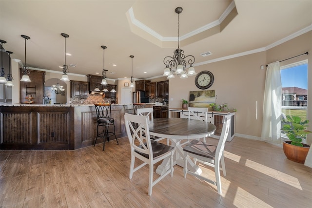 dining room featuring crown molding, light hardwood / wood-style flooring, and a chandelier