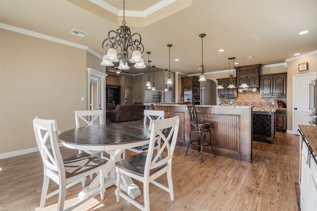 dining space with light hardwood / wood-style flooring, a chandelier, and ornamental molding