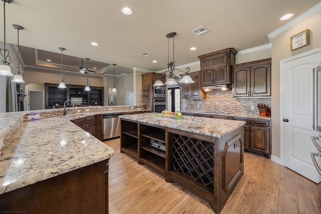 kitchen featuring dark brown cabinets, stainless steel appliances, a spacious island, light hardwood / wood-style floors, and hanging light fixtures