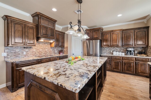 kitchen with dark brown cabinetry, decorative light fixtures, a kitchen island, and high end fridge