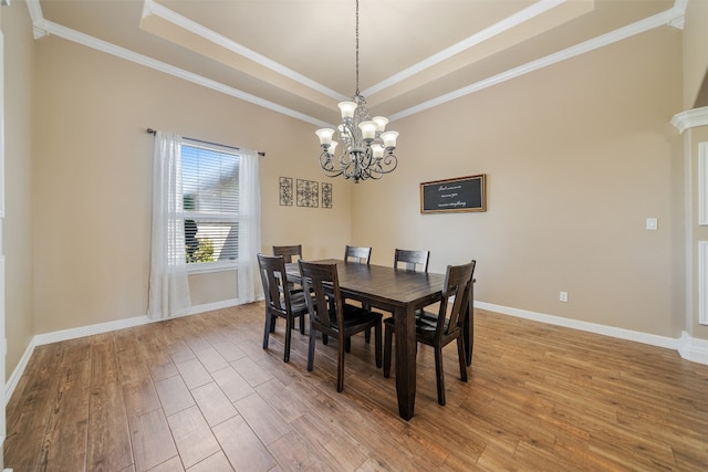 dining space with hardwood / wood-style flooring, an inviting chandelier, crown molding, and a tray ceiling