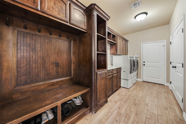 washroom with cabinets, washer and dryer, and light hardwood / wood-style floors