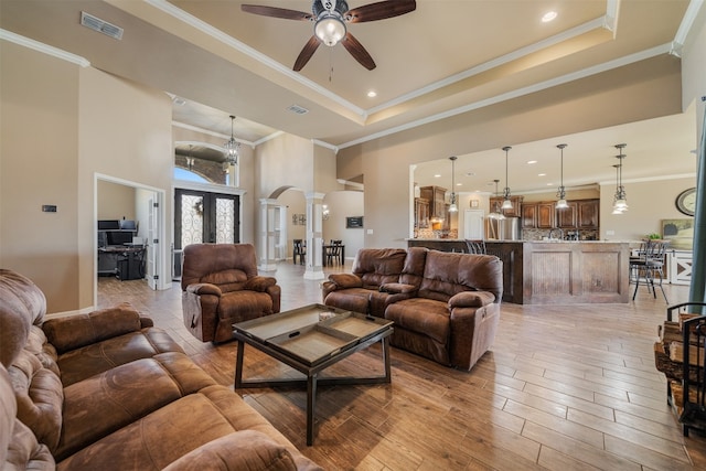 living room with french doors, light hardwood / wood-style flooring, a high ceiling, and ornamental molding