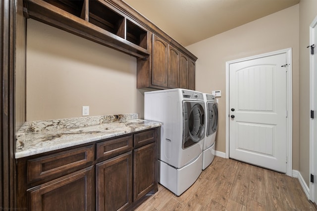 laundry area featuring separate washer and dryer, light hardwood / wood-style flooring, and cabinets