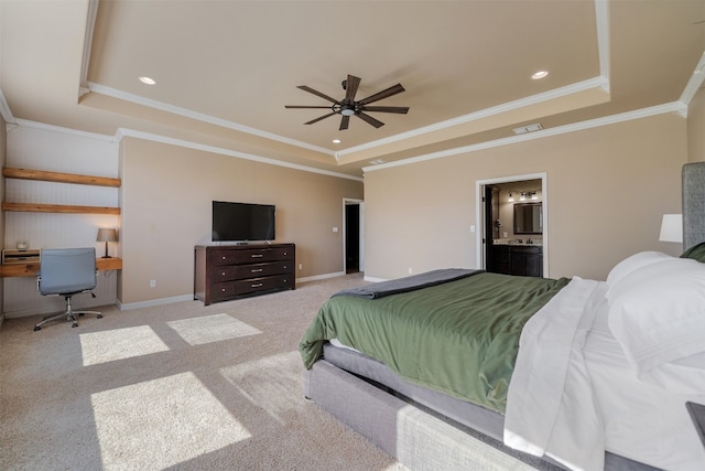 bedroom with a tray ceiling, connected bathroom, and light carpet