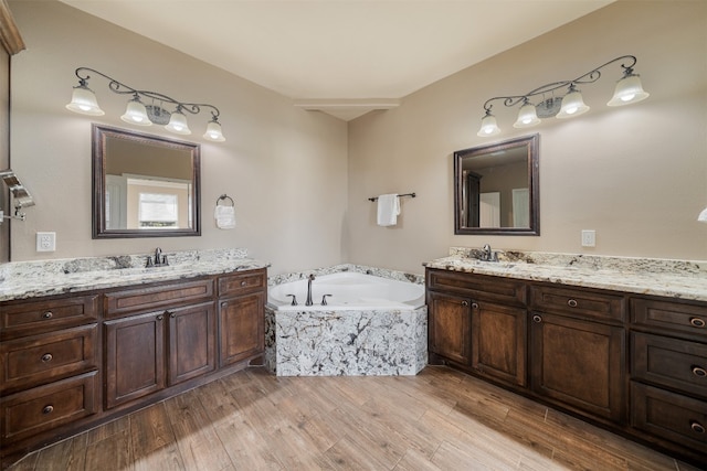 bathroom featuring tiled tub, hardwood / wood-style floors, and vanity