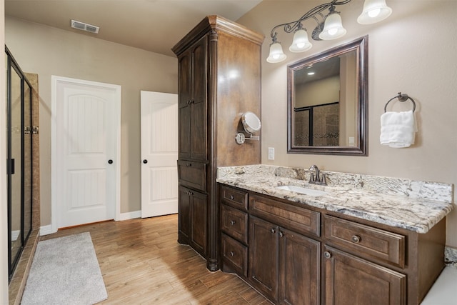 bathroom featuring vanity, a shower, and wood-type flooring