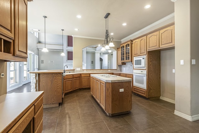 kitchen featuring a center island, kitchen peninsula, pendant lighting, white appliances, and decorative backsplash