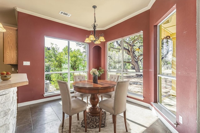 dining space with crown molding, dark tile patterned flooring, and an inviting chandelier