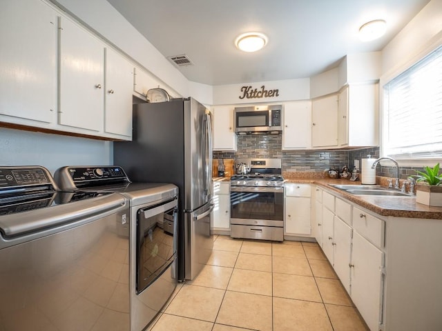 kitchen with washer and clothes dryer, white cabinets, sink, appliances with stainless steel finishes, and light tile patterned flooring