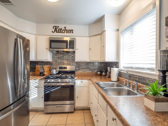 kitchen with light tile patterned flooring, backsplash, stainless steel appliances, and sink