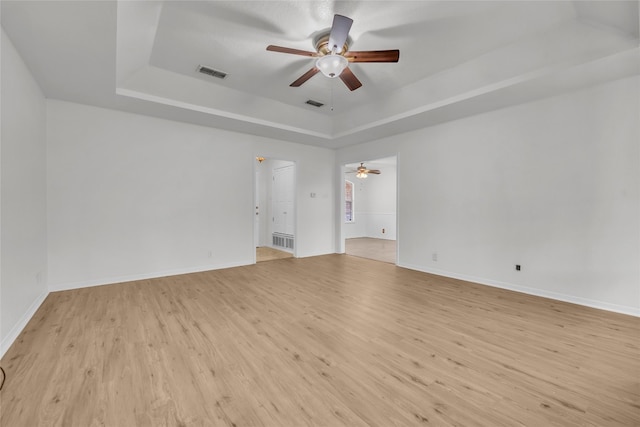 empty room featuring ceiling fan, a raised ceiling, and light hardwood / wood-style flooring