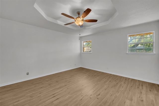 unfurnished room featuring light hardwood / wood-style floors, a raised ceiling, and ceiling fan