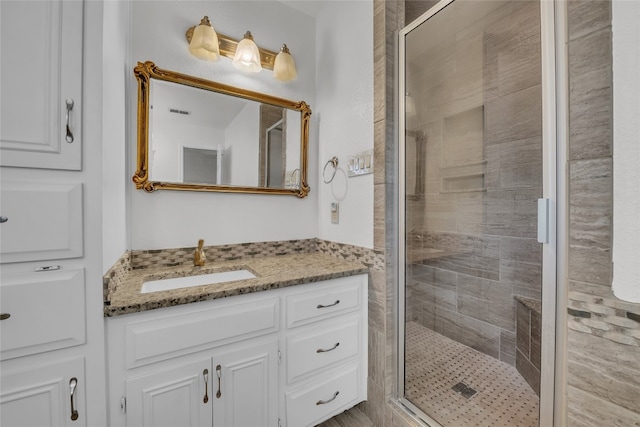 bathroom featuring a shower with door and vanity