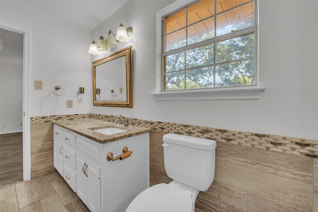 bathroom featuring vanity, tile walls, and toilet