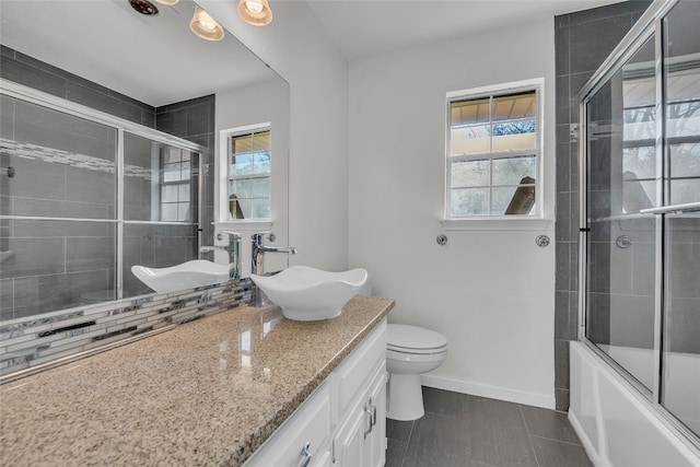 full bathroom featuring shower / bath combination with glass door, vanity, a healthy amount of sunlight, and toilet