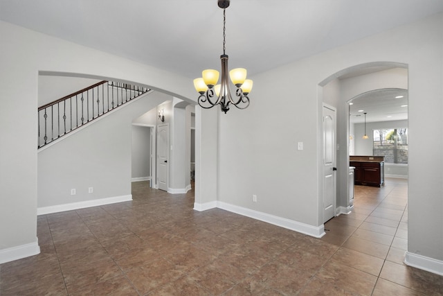 unfurnished dining area featuring dark tile patterned flooring and a notable chandelier