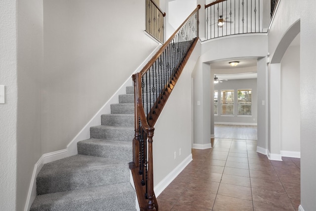 stairs with tile patterned floors, ceiling fan, and a high ceiling