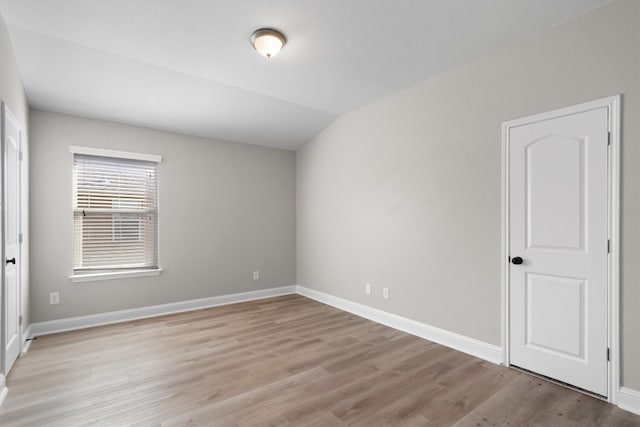 spare room featuring light hardwood / wood-style floors and lofted ceiling