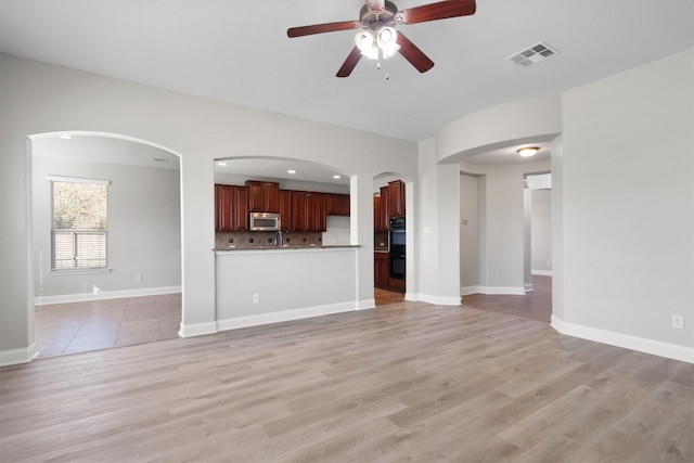 unfurnished living room featuring ceiling fan, light wood-type flooring, and sink