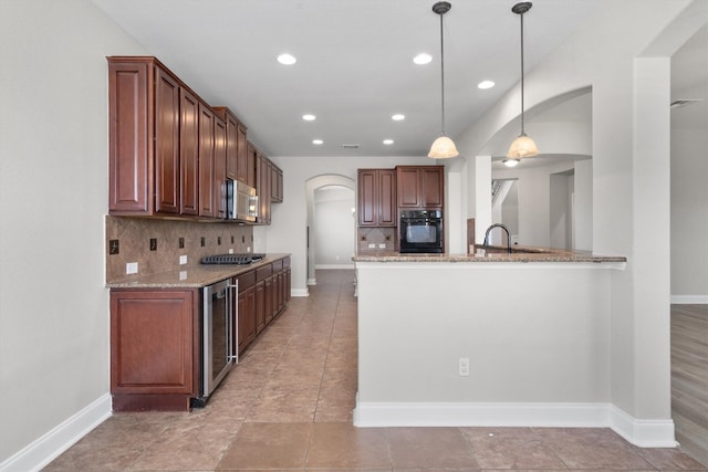 kitchen featuring light stone countertops, backsplash, stainless steel appliances, beverage cooler, and hanging light fixtures