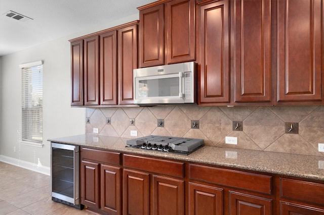 kitchen featuring light stone countertops, beverage cooler, stainless steel appliances, backsplash, and light tile patterned floors