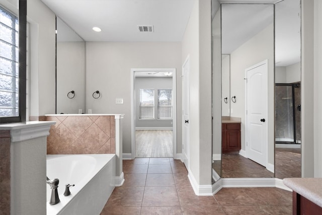 bathroom featuring tile patterned floors, plenty of natural light, a bathing tub, and vanity