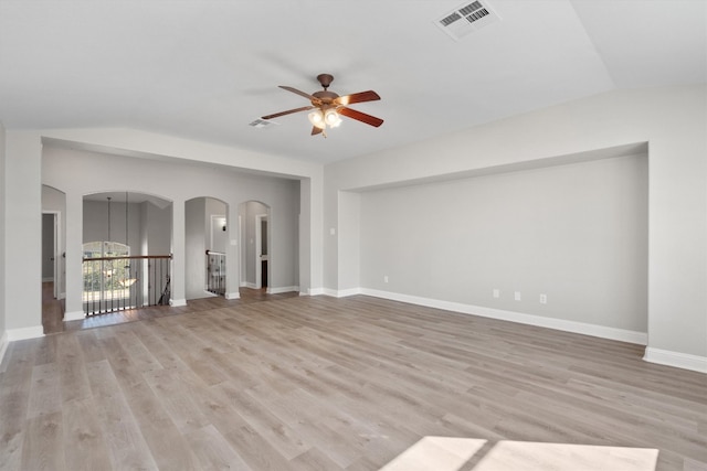 unfurnished living room featuring ceiling fan with notable chandelier, lofted ceiling, and light hardwood / wood-style flooring