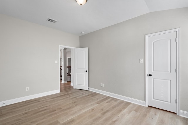 unfurnished bedroom with light hardwood / wood-style flooring and lofted ceiling