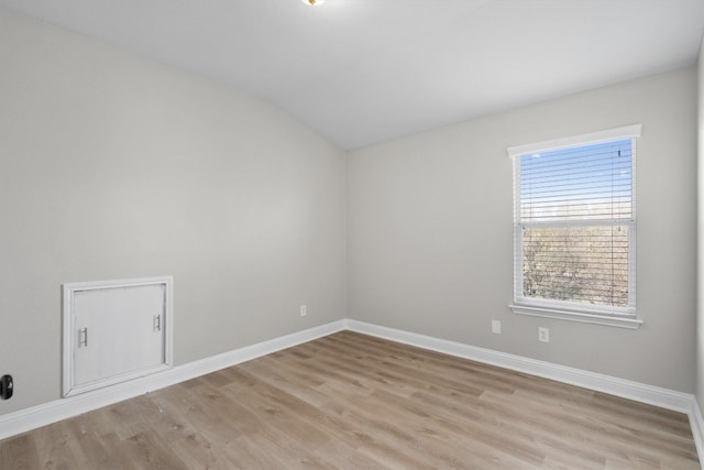 empty room with light hardwood / wood-style floors and lofted ceiling