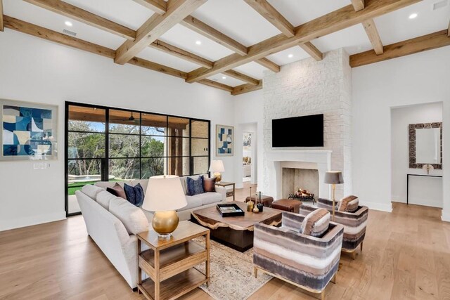 living room featuring coffered ceiling, a fireplace, light hardwood / wood-style floors, and beam ceiling