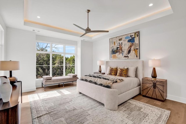 bedroom featuring hardwood / wood-style flooring, ceiling fan, and a tray ceiling