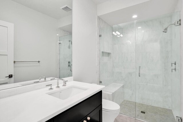 bathroom featuring vanity, toilet, and a shower with shower door