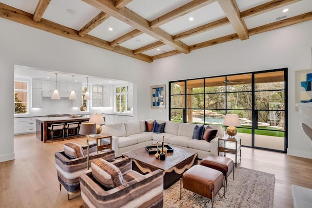 living room with beamed ceiling, a towering ceiling, coffered ceiling, and light hardwood / wood-style floors