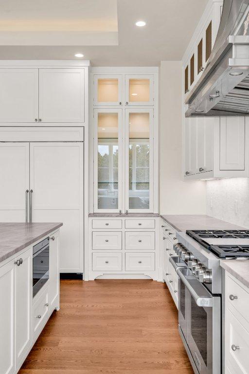 4312 Amarra Dr, Austin, TX 78735 - kitchen with light countertops, white cabinetry, appliances with stainless steel finishes, light wood-type flooring, and wall chimney range hood