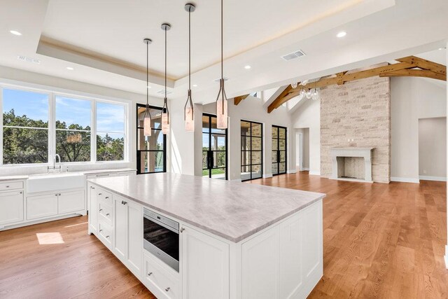 4312 Amarra Dr, Austin, TX 78735 - kitchen with stainless steel microwave, lofted ceiling with beams, a kitchen island, a sink, and visible vents