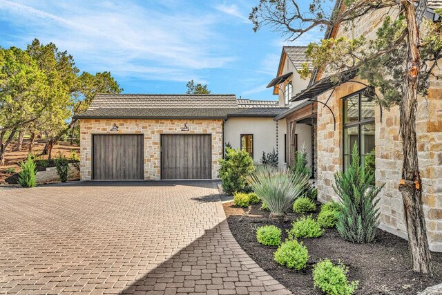 4312 Amarra Dr, Austin, TX 78735 - view of front facade featuring decorative driveway, stucco siding, an attached garage, and stone siding