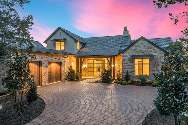4312 Amarra Dr, Austin, TX 78735 - view of front of house with an attached garage, stone siding, french doors, decorative driveway, and a chimney