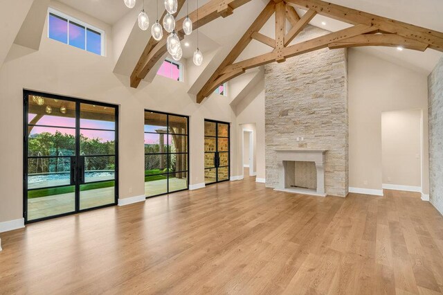 4312 Amarra Dr, Austin, TX 78735 - unfurnished living room with a notable chandelier, a fireplace, baseboards, beamed ceiling, and light wood-style floors
