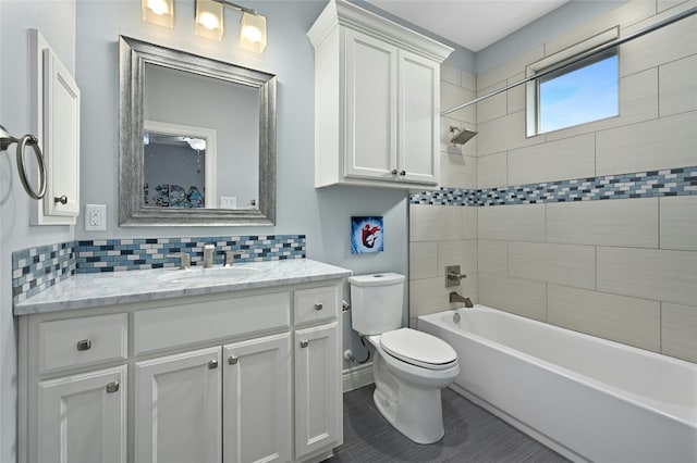 full bathroom with backsplash, tile patterned floors, vanity, toilet, and tiled shower / bath