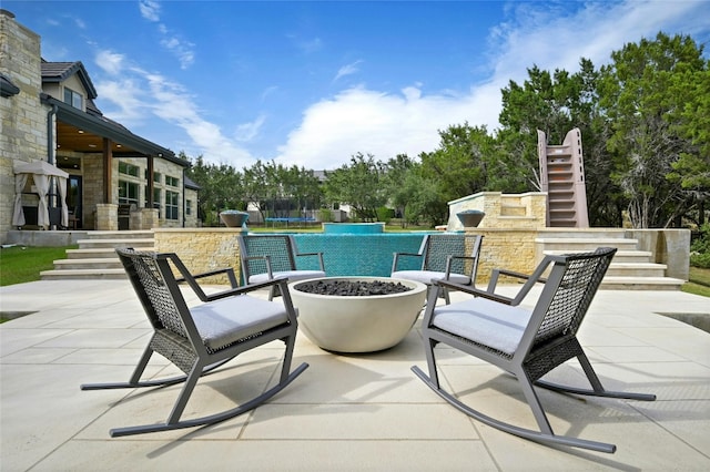 view of patio featuring an outdoor stone fireplace and a trampoline