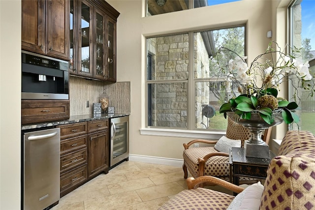 bar featuring dark brown cabinetry, wine cooler, and dark stone counters