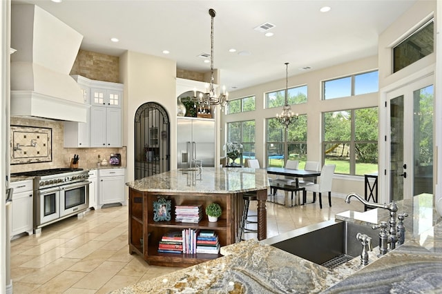 kitchen featuring white cabinets, pendant lighting, high quality appliances, and custom range hood