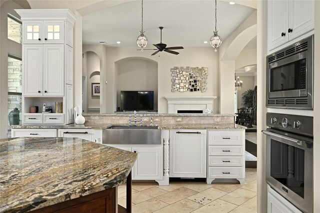 12920 Zen Gardens Way, Austin, TX 78732 - kitchen with appliances with stainless steel finishes, a ceiling fan, open floor plan, arched walkways, and white cabinets