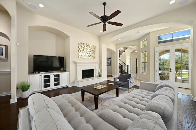 12920 Zen Gardens Way, Austin, TX 78732 - living room featuring stairs, dark wood-style floors, a fireplace with raised hearth, recessed lighting, and arched walkways