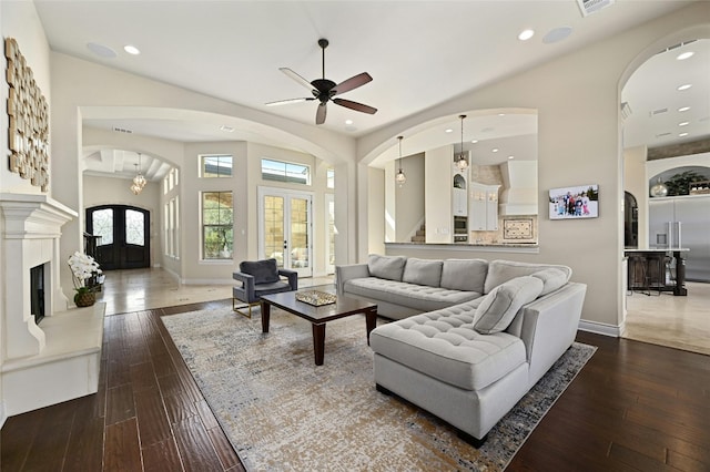 living room with dark hardwood / wood-style flooring, french doors, ceiling fan with notable chandelier, and lofted ceiling