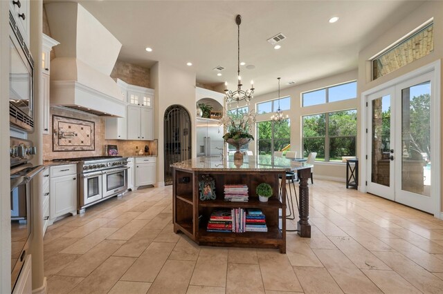 12920 Zen Gardens Way, Austin, TX 78732 - kitchen with custom exhaust hood, appliances with stainless steel finishes, a chandelier, open shelves, and tasteful backsplash