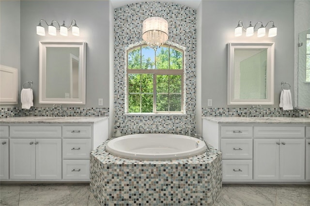 12920 Zen Gardens Way, Austin, TX 78732 - full bathroom featuring marble look tile flooring, two vanities, a garden tub, and tasteful backsplash